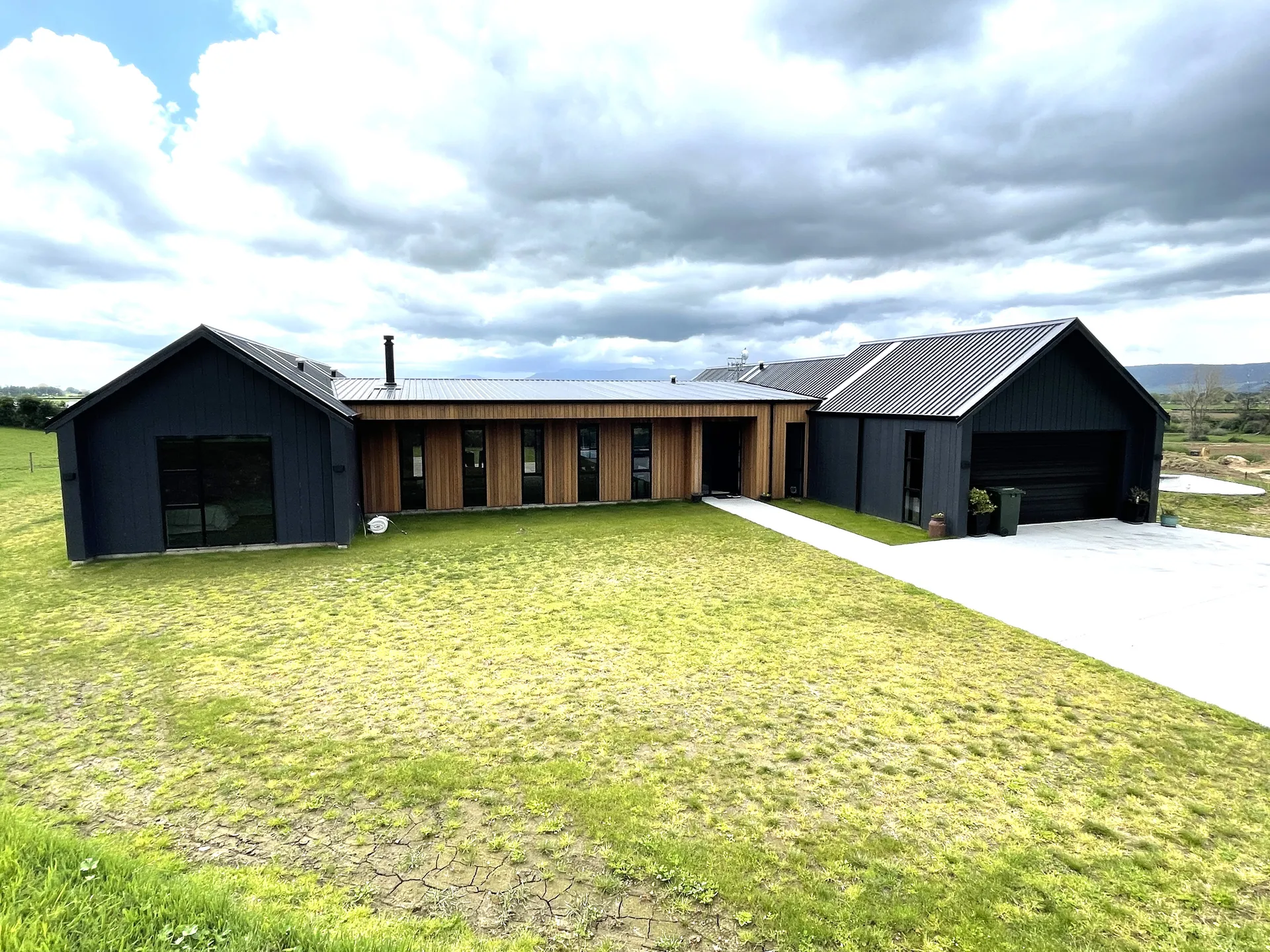 Dark barn-style home with cedar feature cladding and separate garage