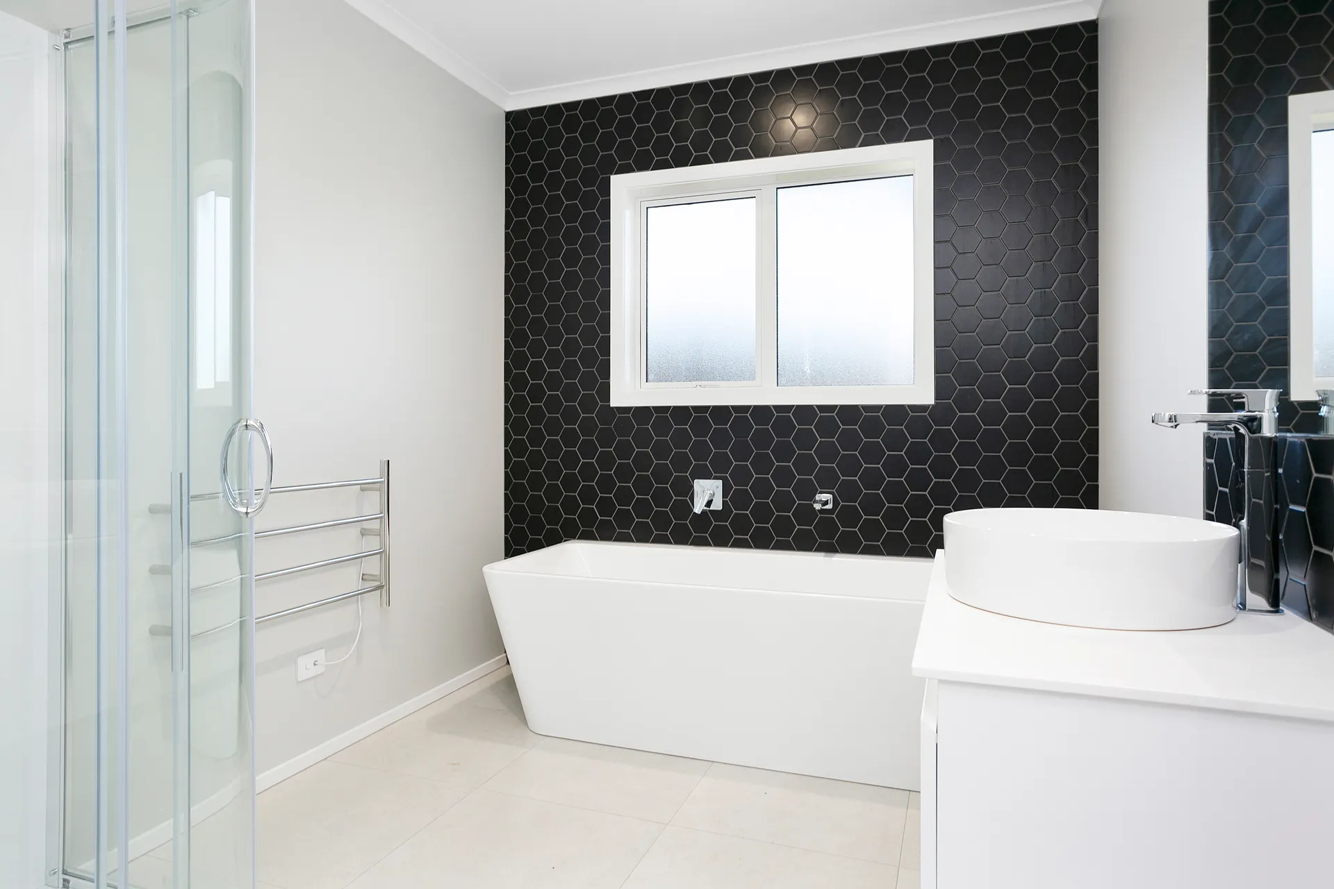 Bathroom with hexagonal tile feature wall and freestanding bath