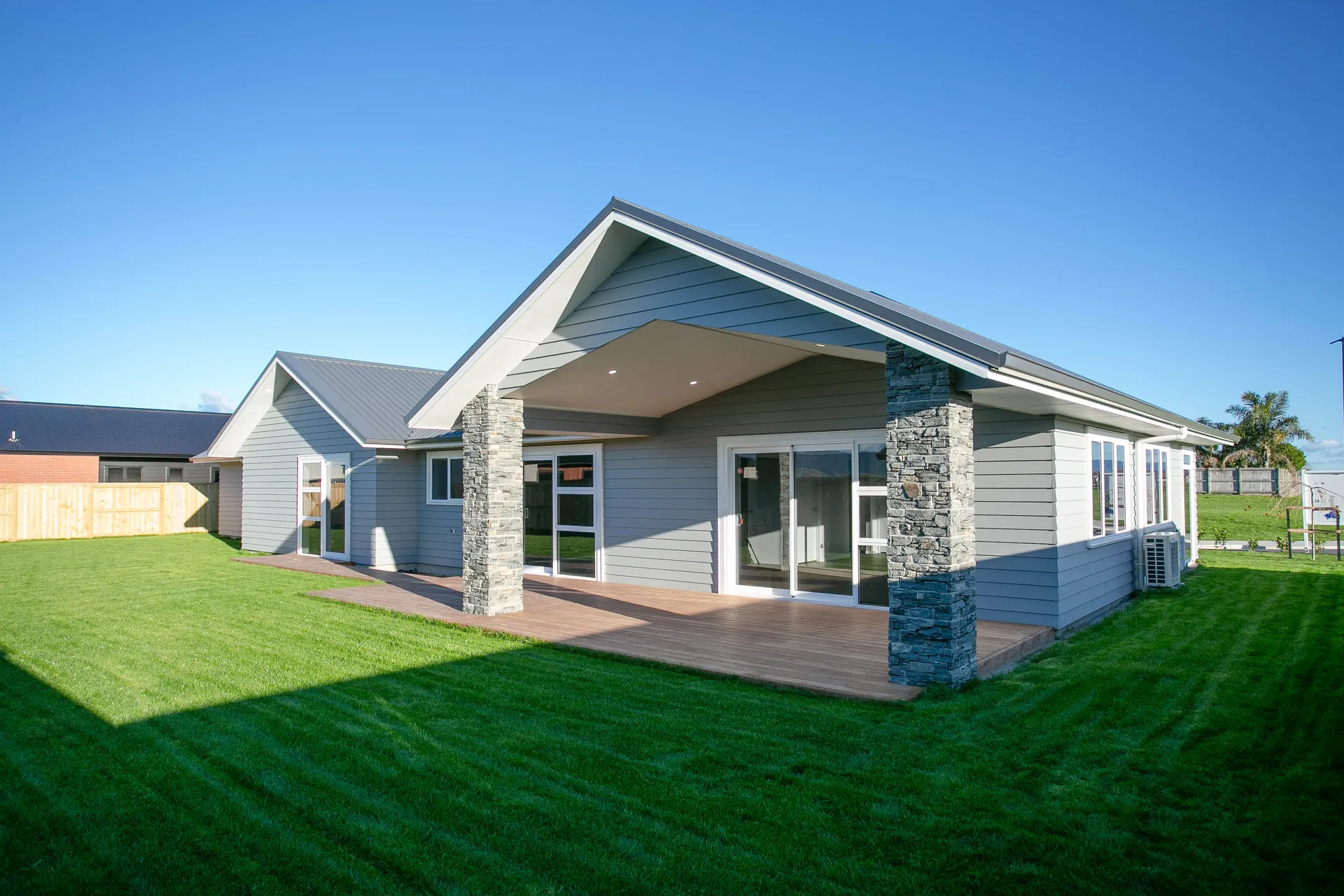 Weatherboard home with stone columns and covered deck