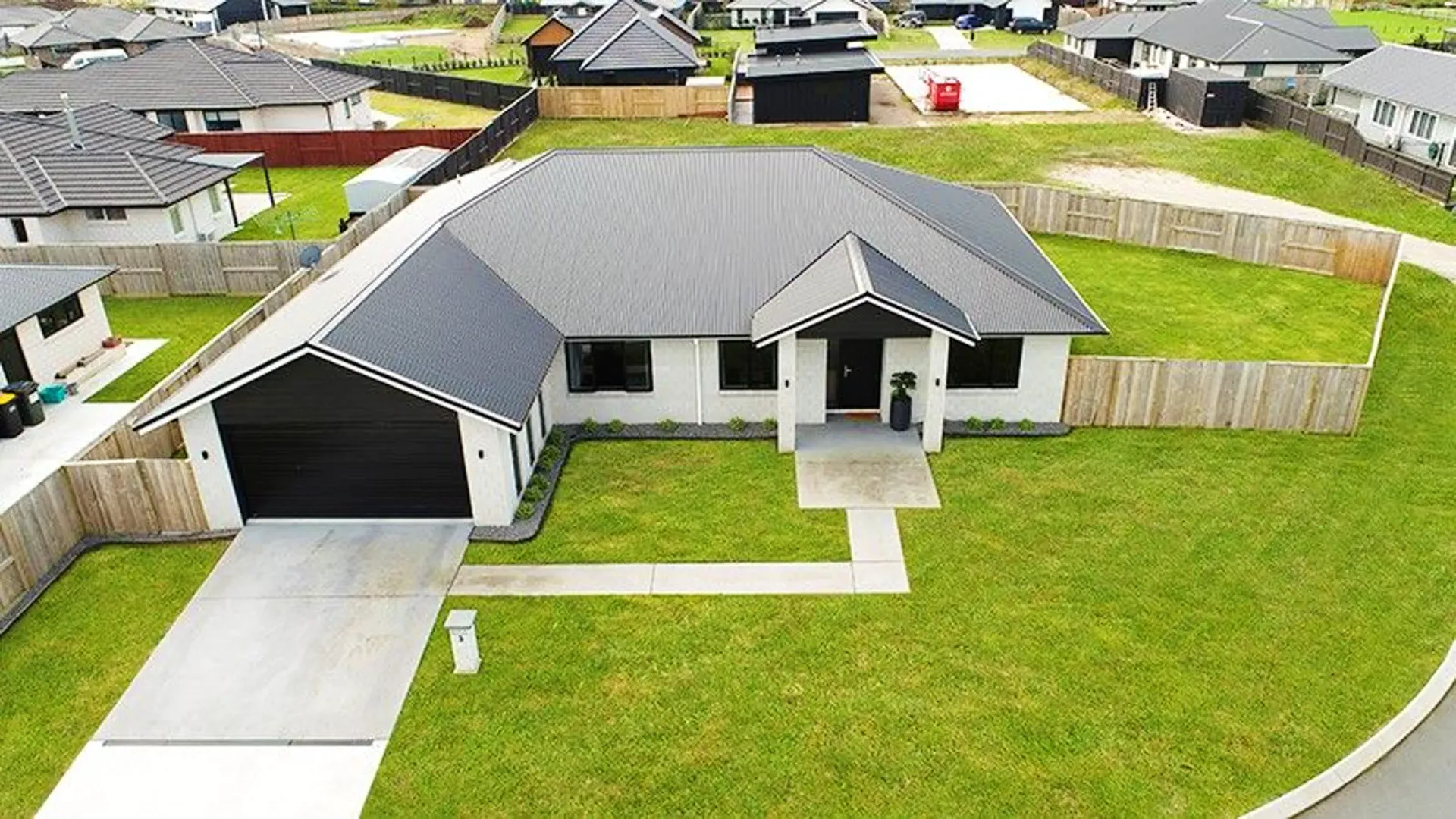 Aerial view of white block home with hip roof on subdivision