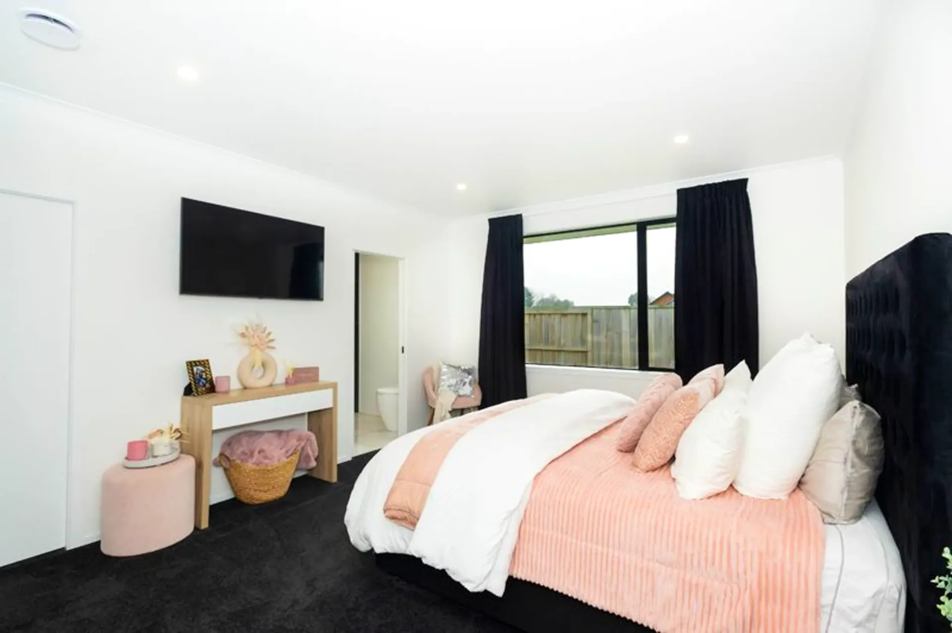 Master bedroom with dark carpet and wall-mounted TV